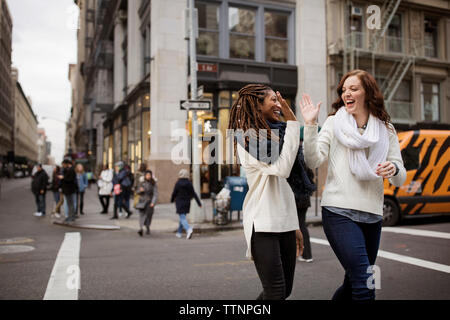 Gerne weibliche Freunde hoch fünf beim Gehen auf die Straße Stockfoto