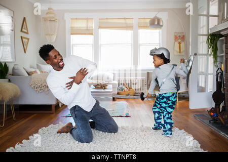 Happy Boy schlagenden Vater mit künstlichen Schwert zu Hause Stockfoto