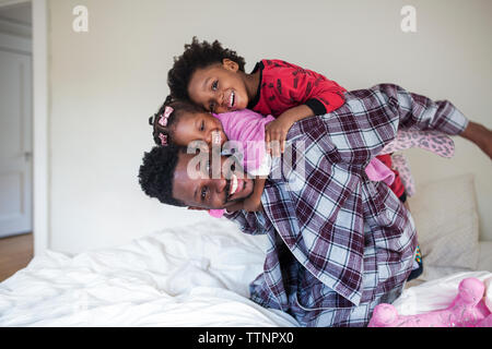 Fröhliche Kinder genießen Huckepack auf Vater im Schlafzimmer Stockfoto