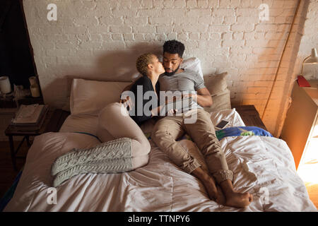 Ansicht von oben Der romantische Frau küssen Mann mit Tablet-PC auf dem Bett