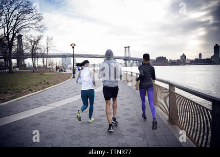 Ansicht der Rückseite des multi-ethnischen Athleten auf Fußweg mit Williamsburg Bridge im Hintergrund Stockfoto