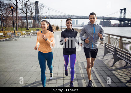 Glücklich, multi-ethnischen Athleten auf Fußweg mit Williamsburg Bridge im Hintergrund Stockfoto