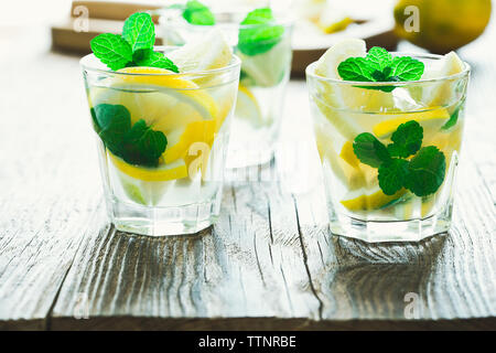 Frische hausgemachte Limonade mit Zitronenscheiben und frischer Minze auf hölzernen Tisch Stockfoto