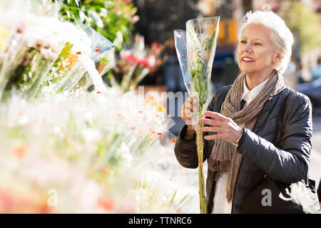 Ältere Frau Kaufende Blumen am Marktstand Stockfoto