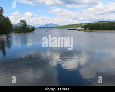 Einen malerischen Blick auf Loch Lomond an einem sonnigen Tag, mit den Bergen in der Ferne und der Raddampfer "Beihilfe des Loch' auf der einen Seite günstig. Stockfoto