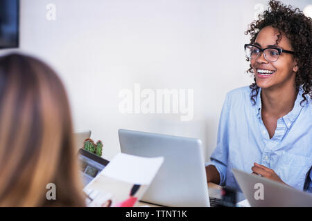Lächelnd Geschäftsfrau mit Kollegen an der Konferenz Tabelle im Board Room Stockfoto
