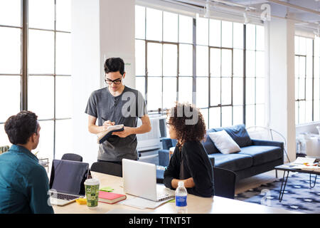 Geschäftsleute, die während der Besprechung im Büro am Schreibtisch diskutieren Stockfoto