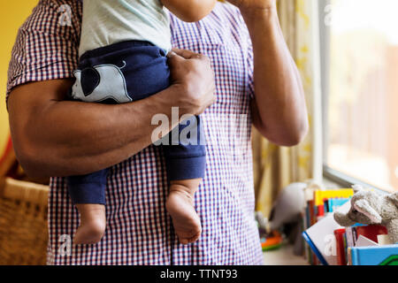 Mittelteil der Vater mit Sohn, während man durch die Fenster zu Hause Stockfoto