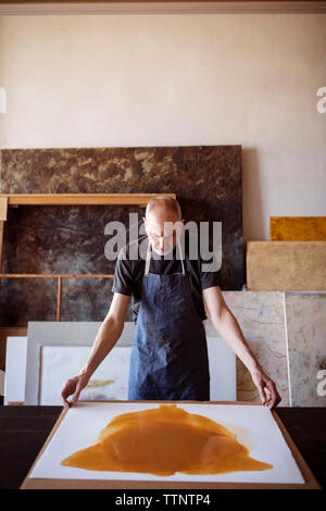 Zuversichtlich Senior Artist holding Malerei am Tisch in der Werkstatt Stockfoto