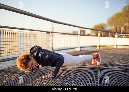 Seitenansicht der entschlossene junge Frau tun Push-ups auf metallischen Fußweg Stockfoto