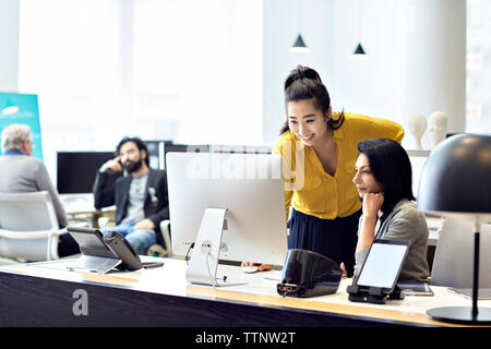 Geschäftsfrauen arbeiten am Desktop-Computer mit männlichen Kollegen im Hinterland Stockfoto