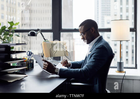 Ernsthafte Geschäftsmanns, der während der Sitzung gegen die Fenster im Büro Stockfoto