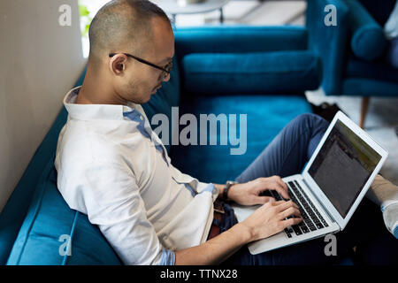 Hohe Betrachtungswinkel der Geschäftsmann mit Laptop während auf blauen Sofa auf kreative Büro zu sitzen Stockfoto