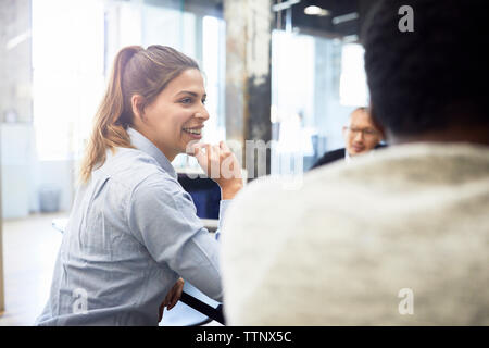 Lächeln, Geschäftsfrau, Sitzen mit männlichen Kollegen, die sich für Treffen im Büro Stockfoto