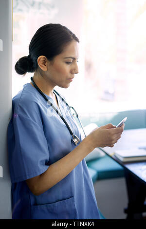 Ärztin mit Smart Phone während im Krankenhaus zu arbeiten Stockfoto