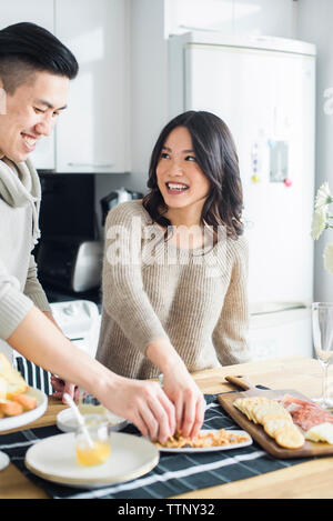 Glückliches Paar in Essen, während am Esstisch in der Küche stehend Stockfoto