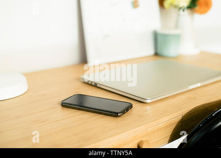 Hohe Betrachtungswinkel der Laptop mit Handy auf hölzernen Schreibtisch im Büro Stockfoto