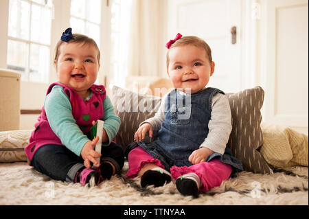 Fröhliches Baby Mädchen sitzen auf Teppich zu Hause