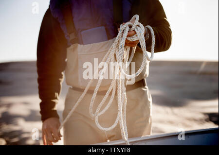 Mittelteil der Mann mit Seil, während am Strand stehen Stockfoto