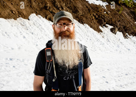 Portrait von zuversichtlich Mann stand auf schneebedeckten Berg Stockfoto