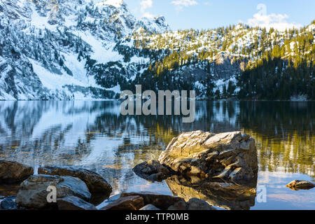 Landschaftlich schöne Aussicht auf ruhigen See gegen schneebedeckten Berg im Wald Stockfoto