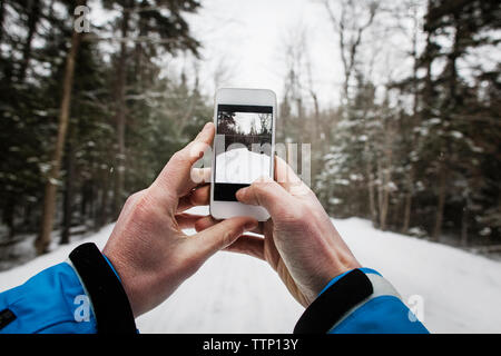 Zugeschnittenes Bild von Hand Schnee fotografieren überdachten Weg mit dem Mobiltelefon Stockfoto