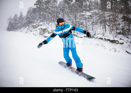 Man Snowboarden von Bäumen auf schneebedeckten Berg Stockfoto