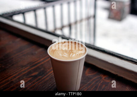 In der Nähe von Cappuccino am Tisch am Fenster serviert. Stockfoto