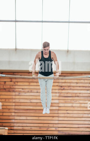 Volle Länge des gymnast Ausübung auf Kip im Fitnessstudio Stockfoto