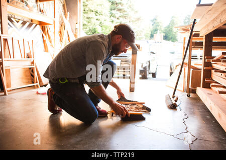 Die ganze Länge der Handwerker Reinigung Holzspäne auf dem Boden in der Werkstatt Stockfoto