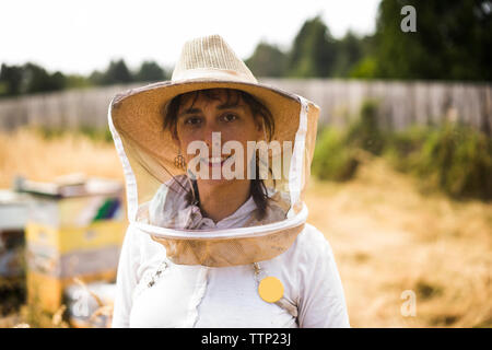 Portrait von weiblichen Imker durch das Tragen von schützender Maske und Hut auf dem Feld Stockfoto