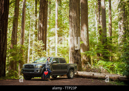 Weibliche Wanderer lehnte sich gegen Pick-up Truck in Wald im Redwood National- und Staatsparks Stockfoto