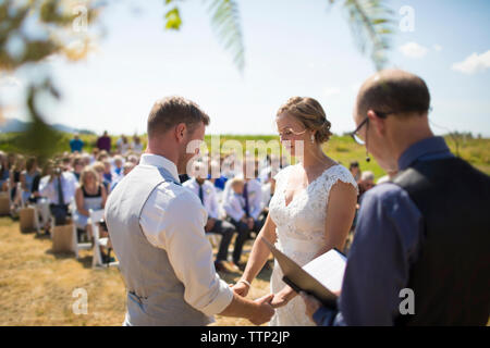 Junges Paar durch Priester während sonniger Tag verheiratet Stockfoto