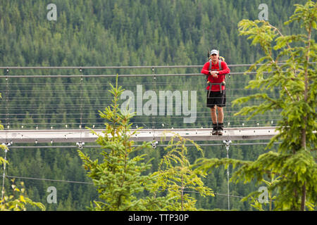 Wanderer mit Rucksack auf Steg inmitten Wald Stockfoto