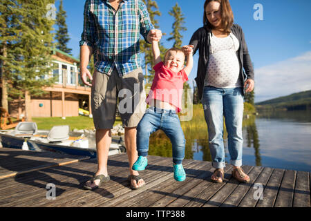 Sohn spielen mit Eltern auf hölzernen Pier über den See Stockfoto