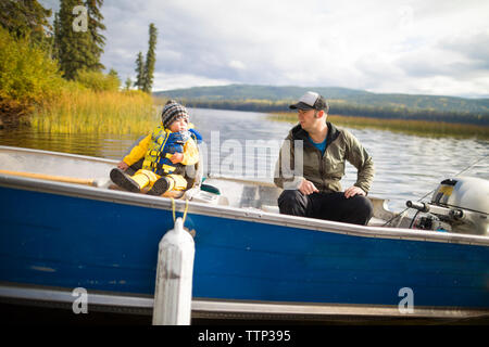Vater und Sohn im Boot sitzen auf See Stockfoto