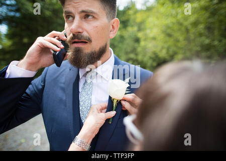 7/8 Bild der Frau einstellen Anstecker für Bräutigam Jacke an Hochzeit Stockfoto