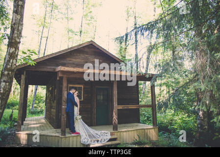 Frisch vermählte Paar küssen beim Stehen in der Halle am Wald Stockfoto