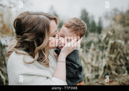 Liebevolle Mutter küssen niedlichen Sohn auf dem Feld Stockfoto