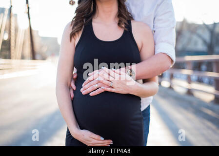Mittelteil der Mann das Berühren der schwangeren Frau Bauch, während auf der Straße Stockfoto