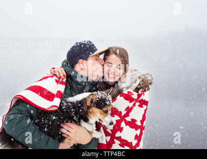 Mädchen drängten sich in der Decke mit Guy & Hund bekommt Überraschung Kuss auf die Wange Stockfoto