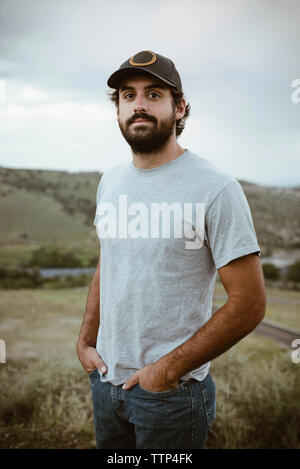 Portrait von zuversichtlich Mann stand mit den Händen in den Taschen in das Feld Stockfoto