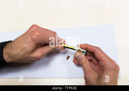 7/8 Hände von Ingenieur schärfen Bleistift am Schreibtisch im Büro Stockfoto