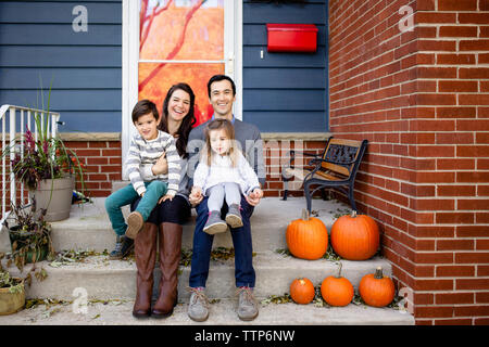 Portrait von Happy Family sitzen auf Schritte gegen Haus während der Halloween Stockfoto