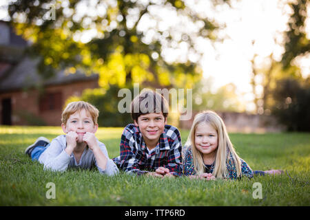 Nette Geschwister nebeneinander verlegen in Feld im Freien Stockfoto