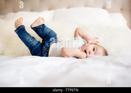 Baby Boy Festlegung auf dem Rücken auf dem Bett bei Camera suchen Stockfoto