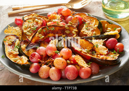 Nahaufnahme von roten Trauben mit acorn Squash in der Platte auf dem Tisch Stockfoto