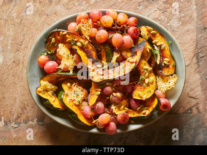 Hohe Betrachtungswinkel von roten Trauben mit acorn Squash in der Platte auf dem Tisch Stockfoto