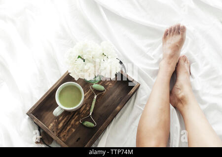 Niedrige Abschnitt der Frau mit Jade und Matcha Tee in Holz- Fach auf dem Bett Stockfoto