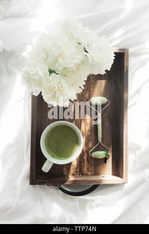 Ansicht von oben von Matcha Tee mit Jade und Blumen in Holz- Fach auf dem Bett Stockfoto